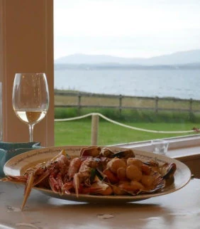 A plate of langoustines and a glass of white wine on the windowsill, with Loch Indaal beyond