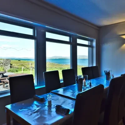 The dining room, tables laid along picture windows looking out over Loch Indaal